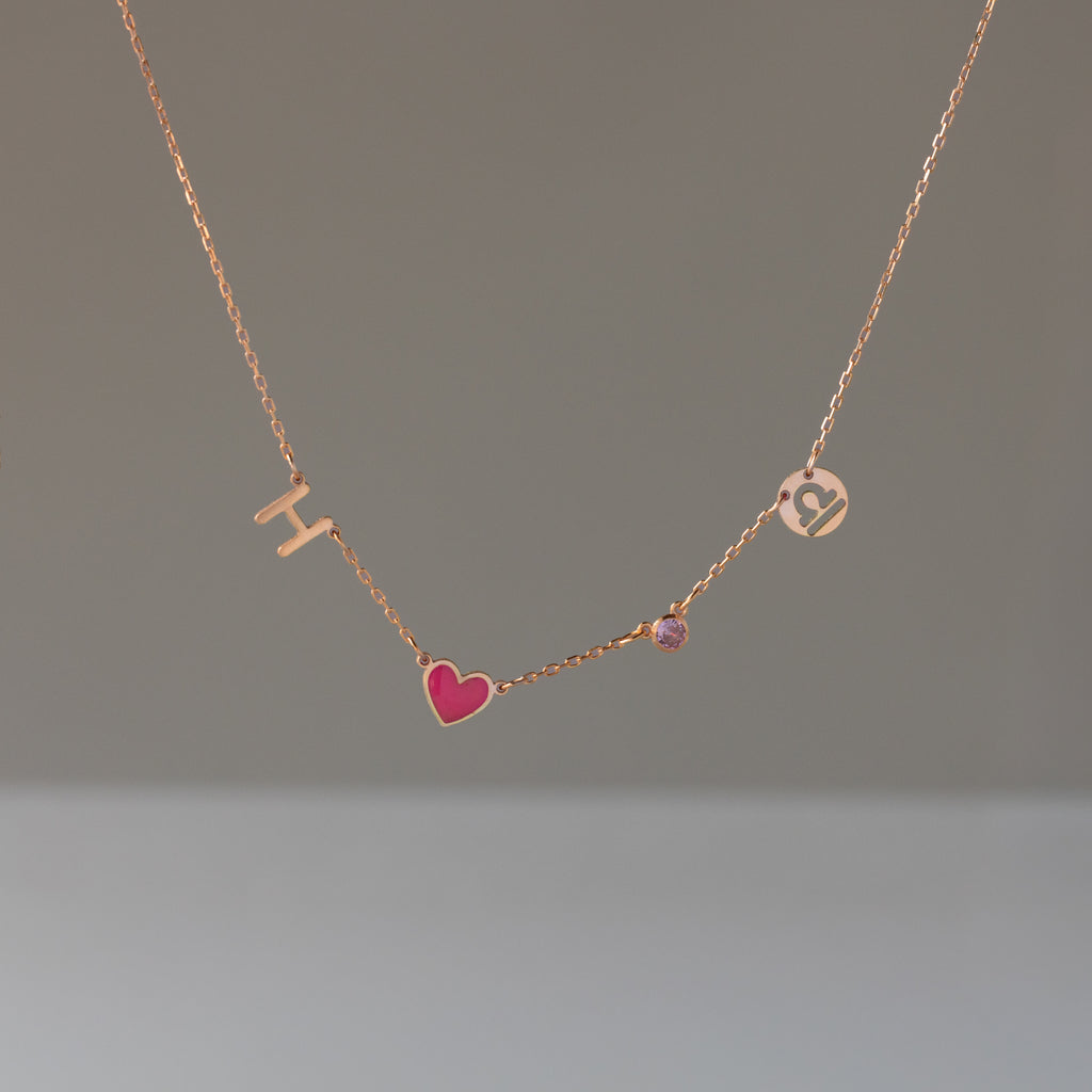Dainty Space Charm Necklace in Rose Gold featuring gold letters H and J, a pink heart, and a small gem—perfect as a personalized gift for any occasion.