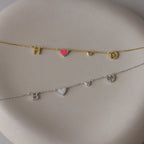 Two delicate bracelets with letter, heart, and symbol charms—one gold-toned, one silver-toned—on a cream surface; perfect for pairing with the Dainty Space Charm Necklace or stacking alongside your favorite birthstone necklace.