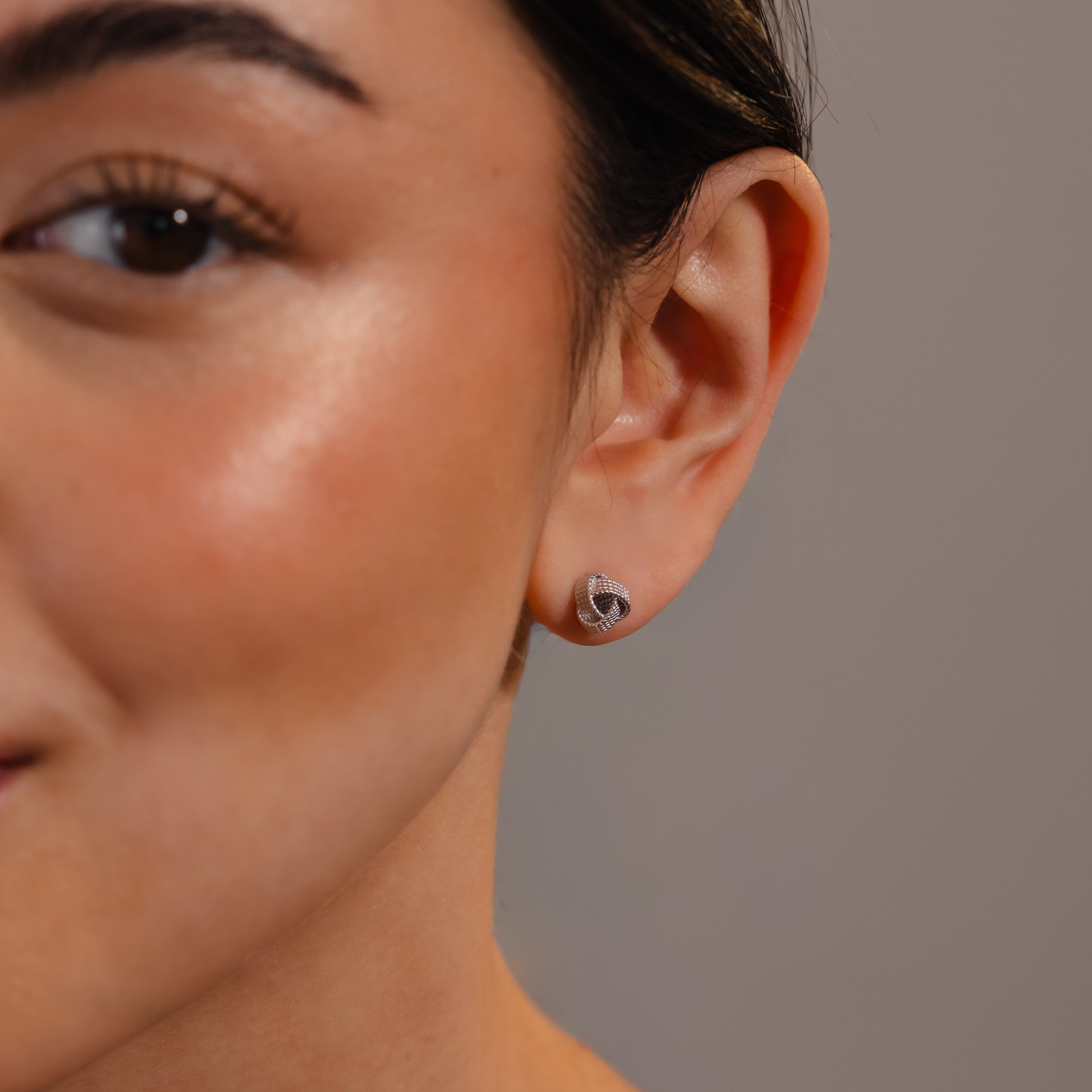 Close-up of a woman's ear wearing Rope Knot Studs—small silver earrings with a textured, knotted design, perfect for anyone seeking understated elegance in their jewelry collection.