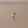 The Pave Dome Charm in Silver glistens with small stones on a smooth, neutral backdrop.
