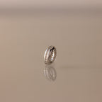 The Pave Dome Charm in Silver glistens with small stones on a smooth, neutral backdrop.