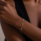 Silver bracelet with small diamond-like stones on a person's wrist against a neutral background