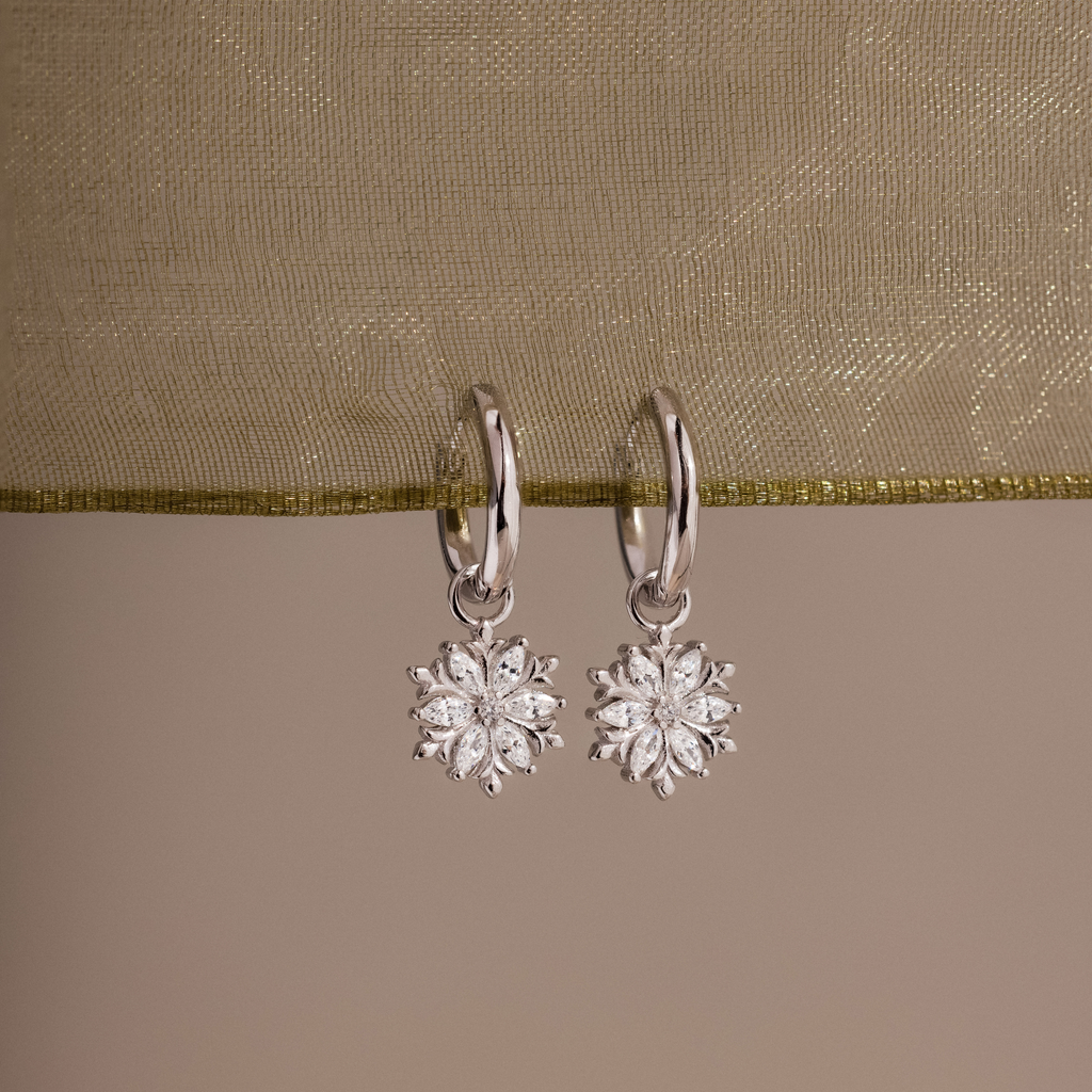 Flatlay of our Diamond Poinsettia Hoops against a green ribbon