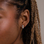 Close-up of a model with a minimalistic silver earring, hair styled in braids.