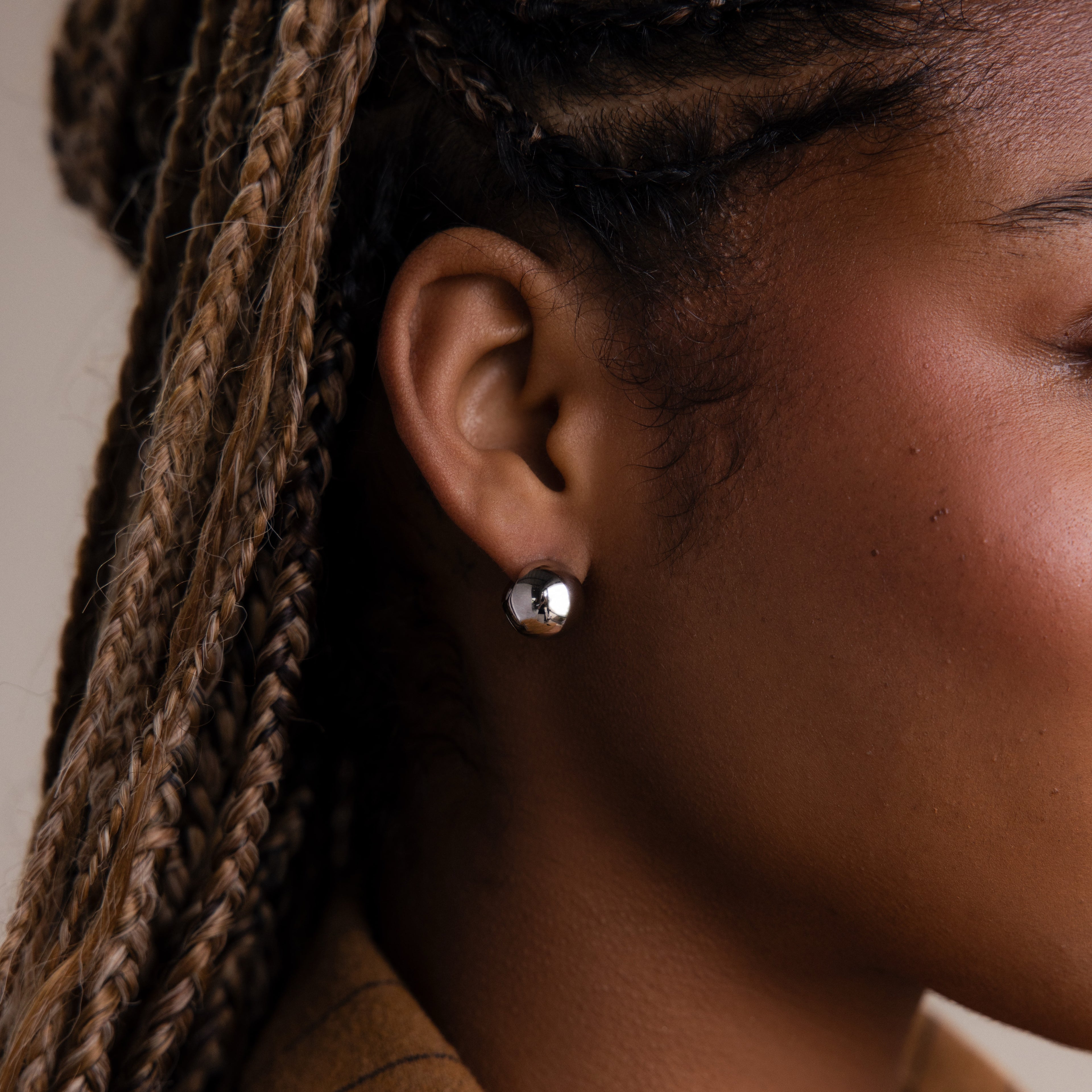 Close-up of a model with a round silver hoop earring, focusing on the jewelry.