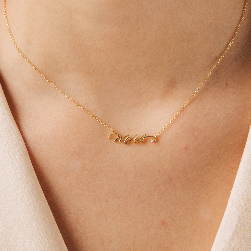 The Mrs. Necklace features elegant gold cursive lettering, designed to be worn around the neck—an ideal and chic wedding gift for any bride-to-be.