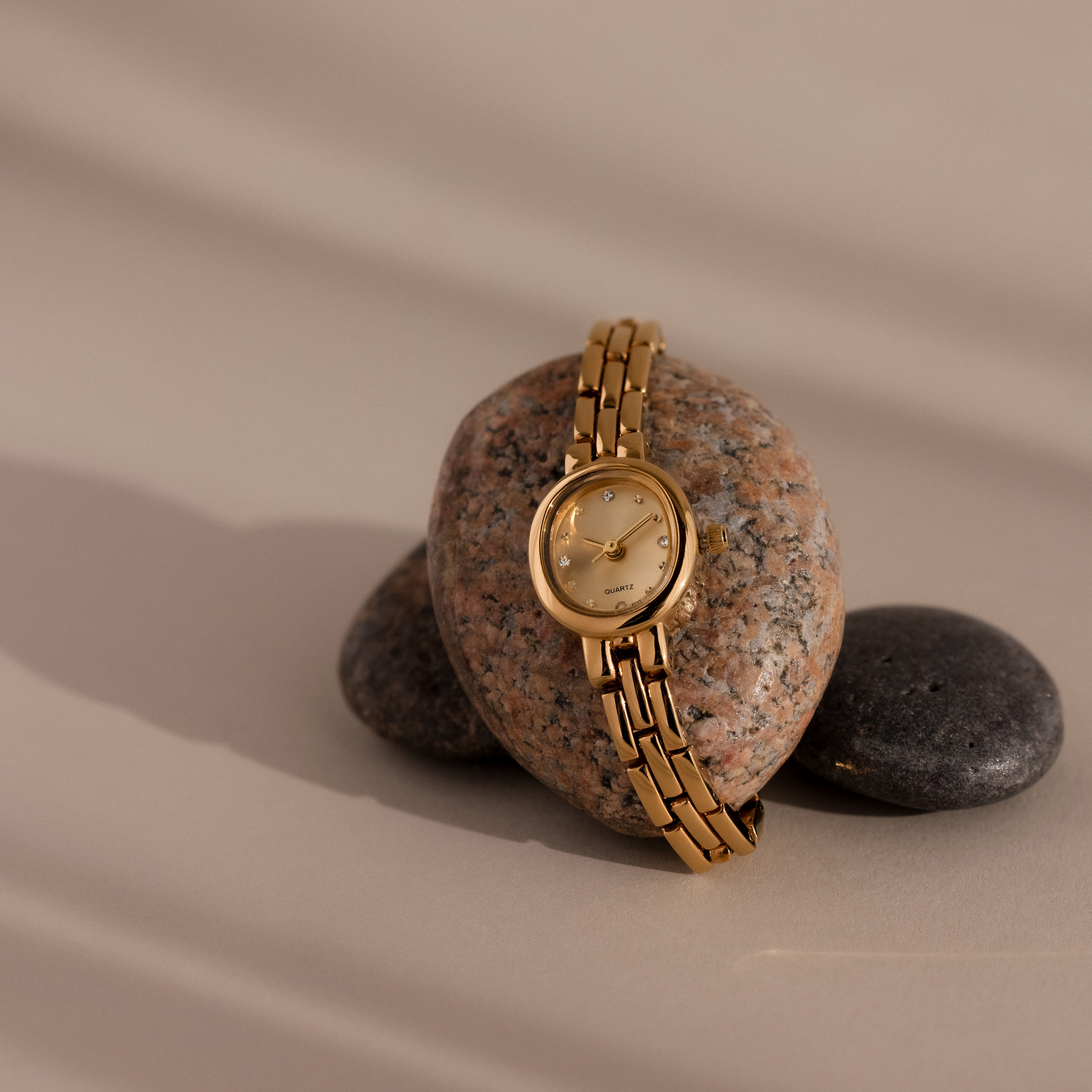 Our Cobblestone Timepiece watch on a stone with a beige background