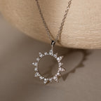 The Pave Sun Necklace features glittering pave accents and small diamonds, showcased against a neutral textured background.