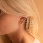 Close-up of a woman's ear wearing the Opal Drop Earrings Set, featuring three gold earrings—each a different style, ideal for layering.