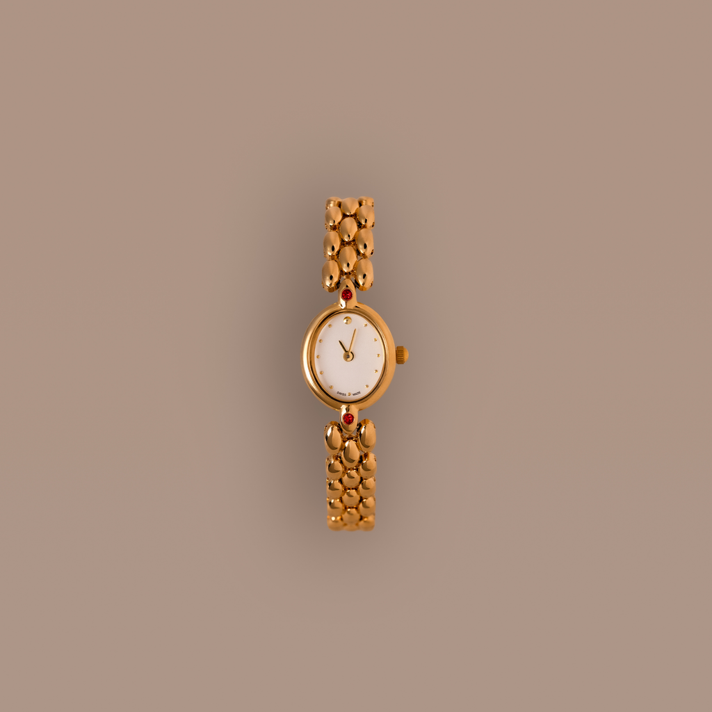 Our Cherry Blossom Timepiece watch with ruby gemstones against a beige background