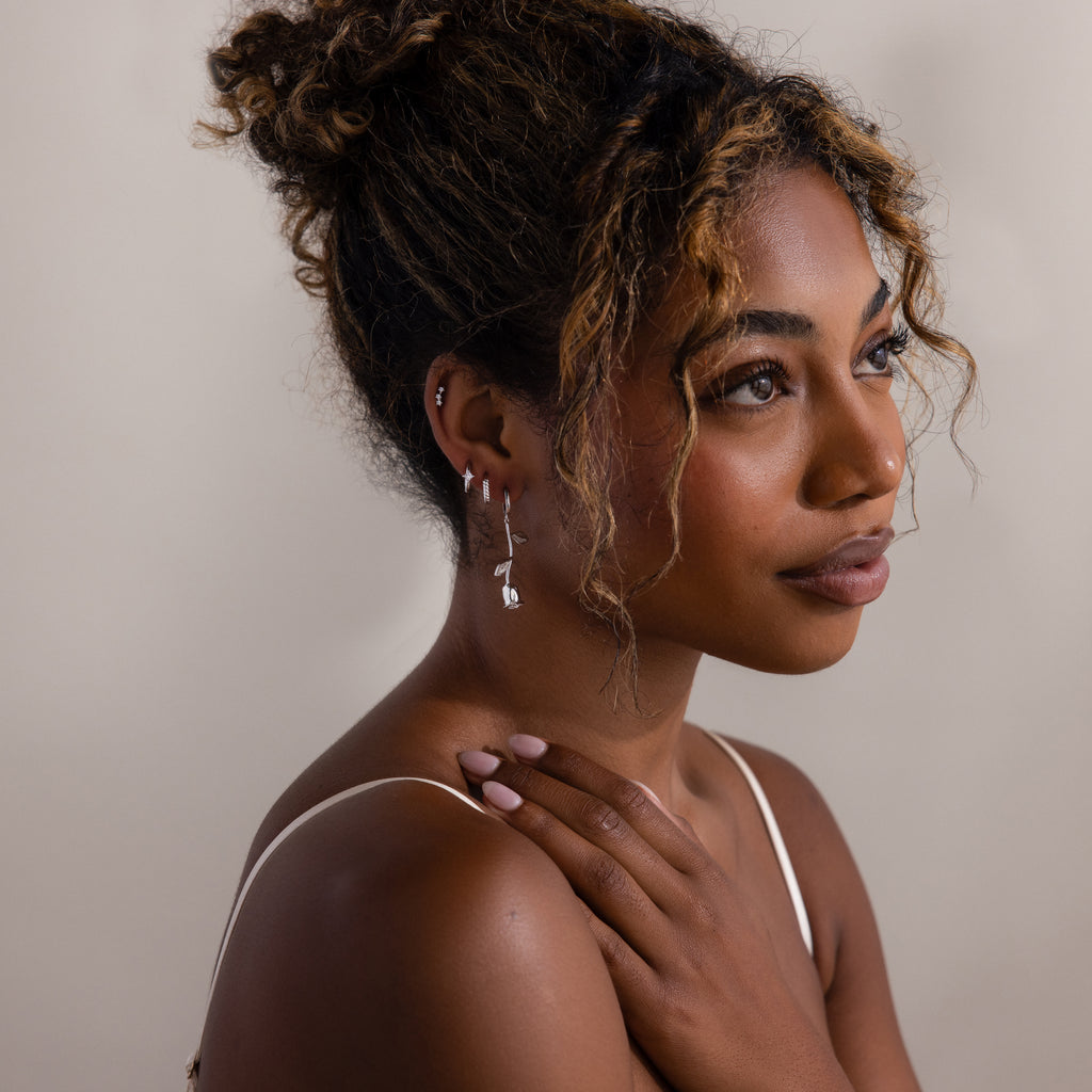 Woman with styled hair and silver earrings against a neutral background