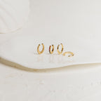Set of various gold cuff earrings on a white surface