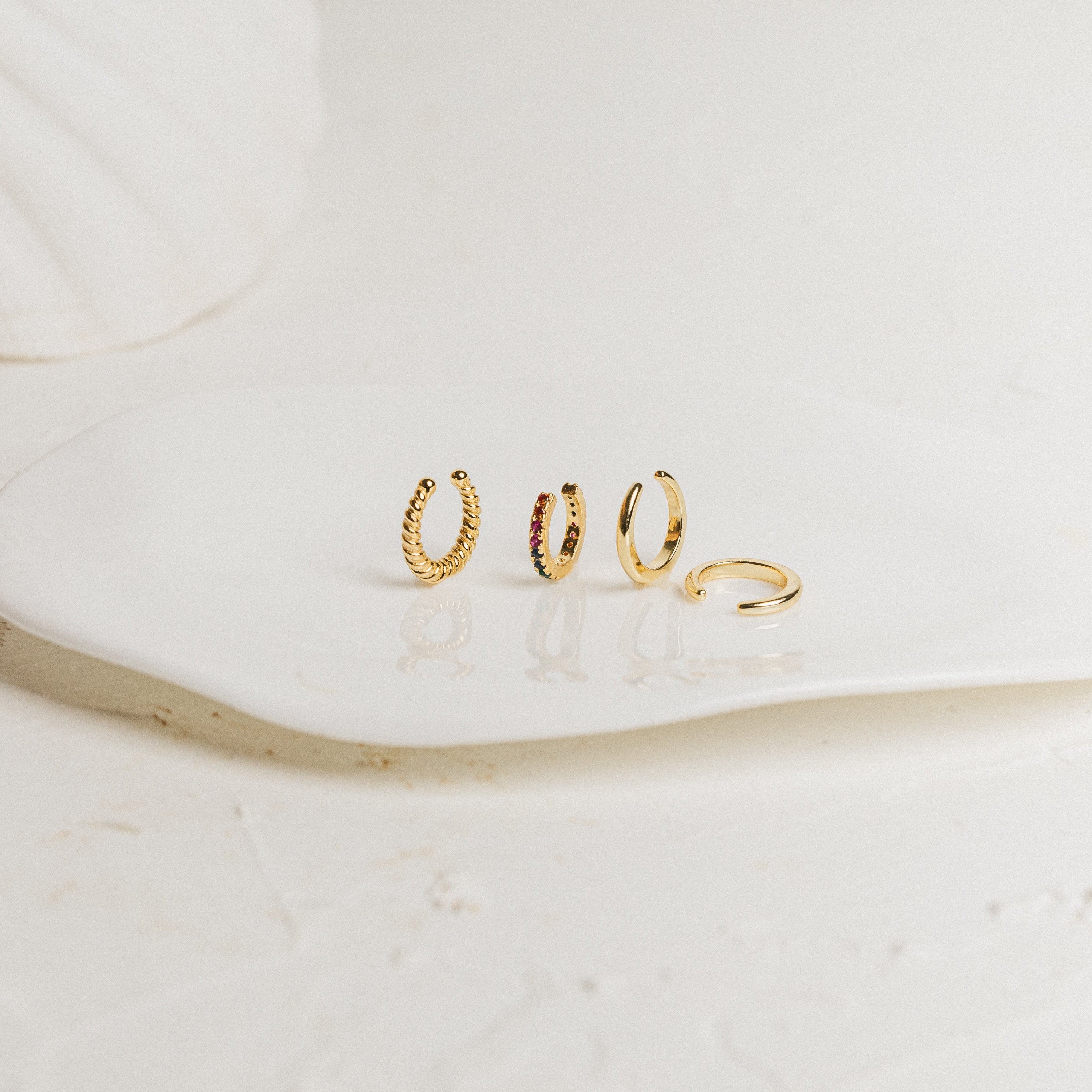 Set of various gold cuff earrings on a white surface