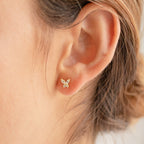 Close-up of a model wearing a delicate gold butterfly earring.