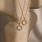 The Pave Sun Necklace—one silver with pave accents, one gold—shines on a textured beige mannequin bust, perfect for showcasing the collection.
