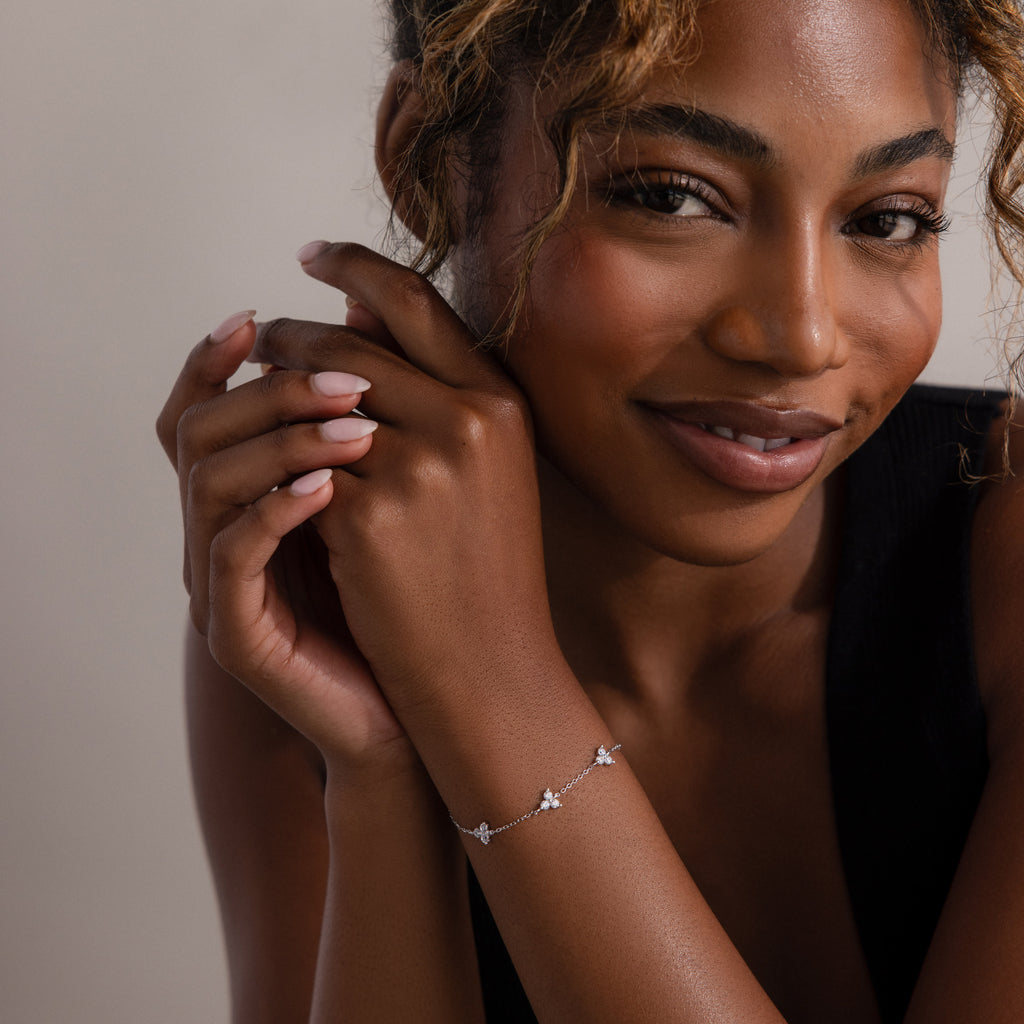 Woman wearing a dainty floral bracelet with a neutral background