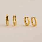 Two pairs of gold hoop earrings in varying sizes on a beige background