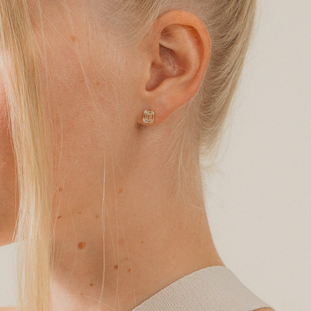 Close-up of a woman wearing gold earrings with a neutral background