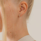 Close-up of a woman wearing gold earrings with a neutral background