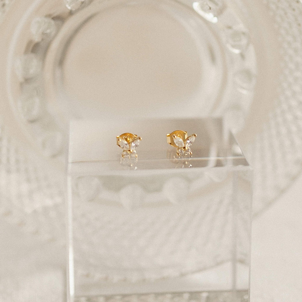 Gold earrings with diamond stones on a decorative translucent plate