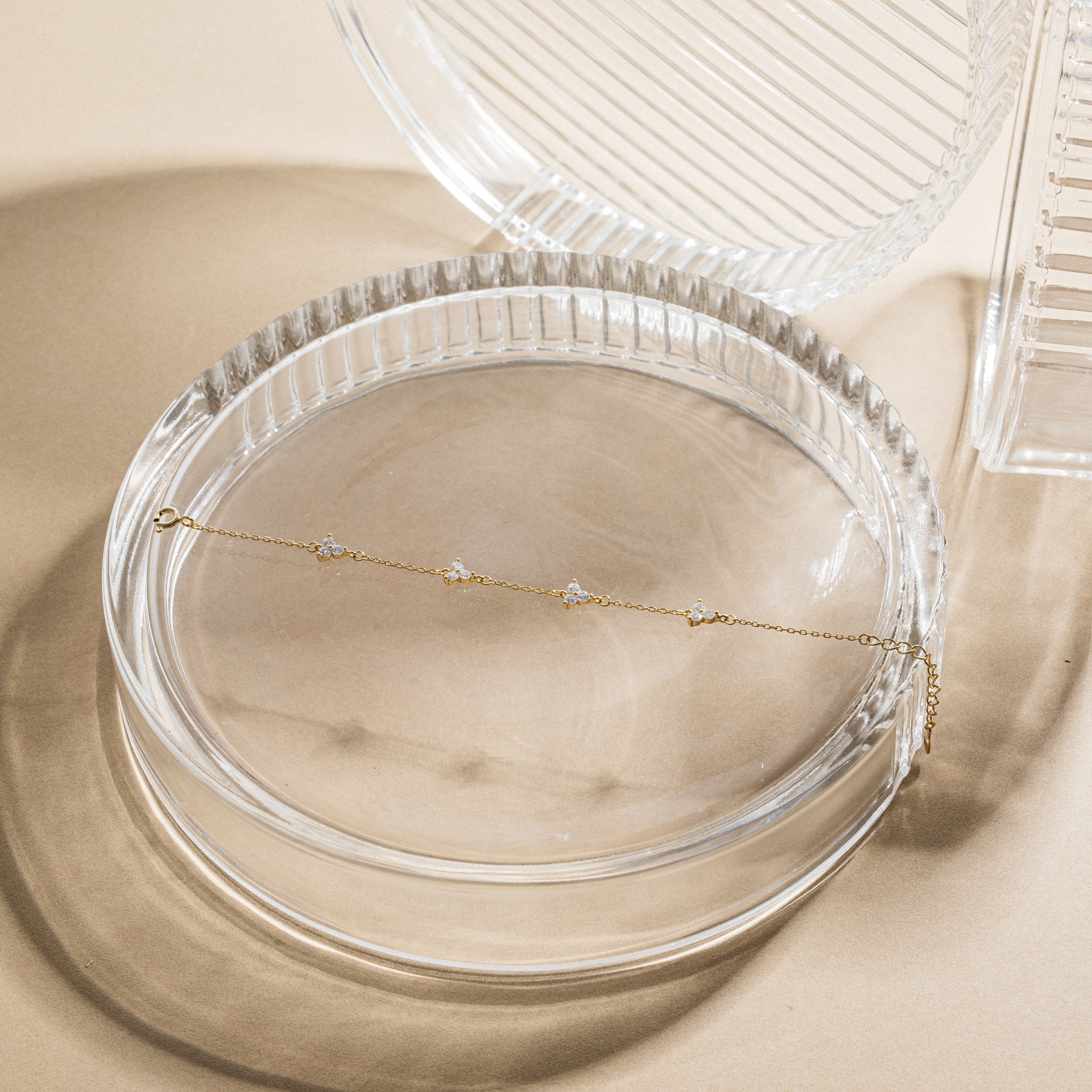 Gold necklace on a clear glass dish with a beige background