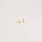 Gold bar earrings on a light beige background