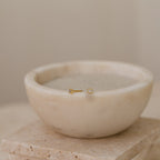 Gold diamond cluster stud earrings in a marble bowl on a neutral background