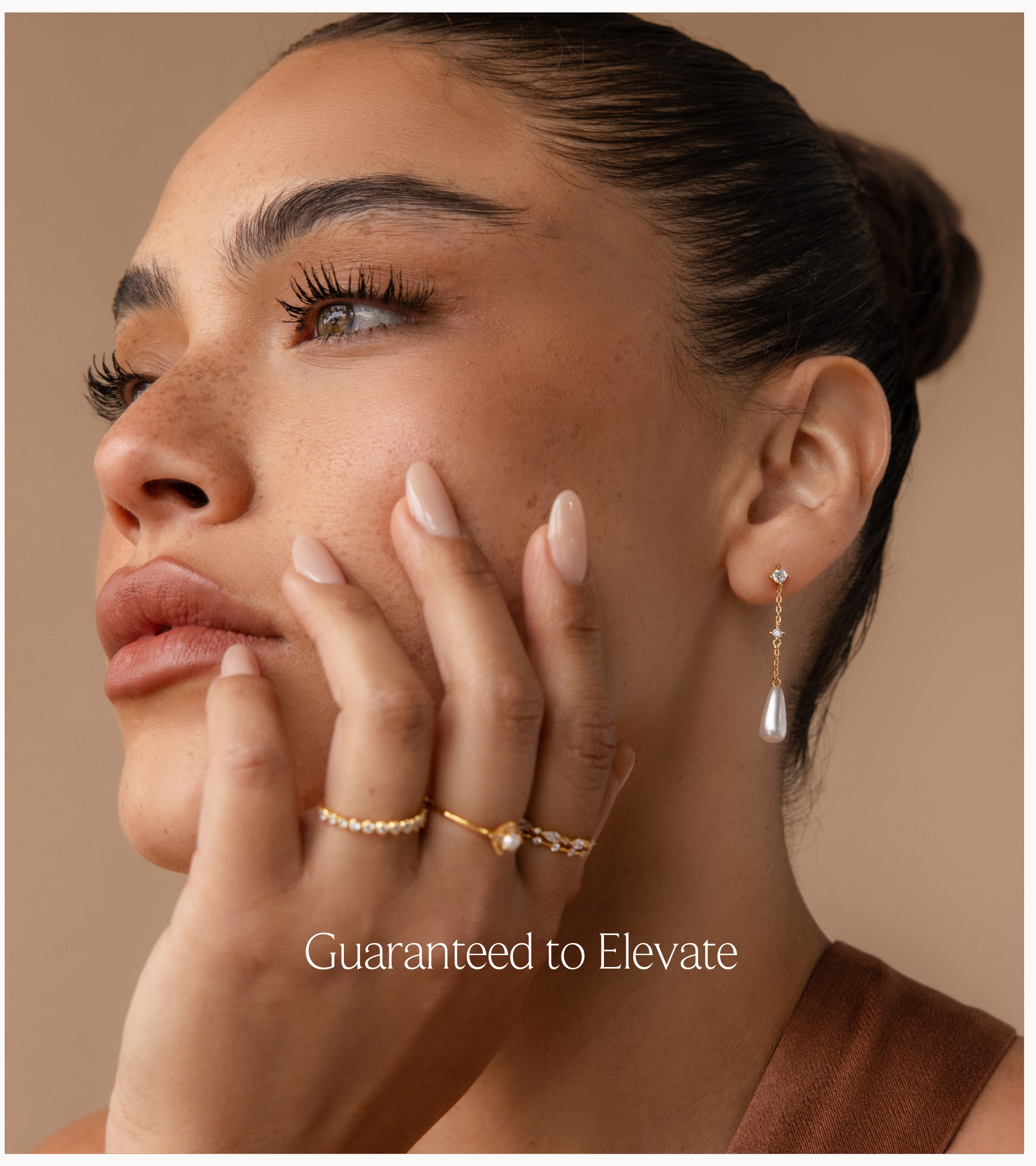 A banner with text "guaranteed to elevate" featuring a jewelry model photo of a gold jewelry stack consisting of a diamond and pearl chain drop earring, 1 diamond ring, 1 pearl ring and a diamond ring set.