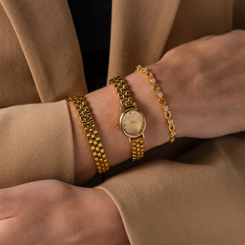 A person wearing the Oval Link Timepiece Set on their wrist, paired with a tan blazer.