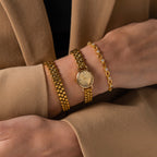 A person wearing the Oval Link Timepiece Set on their wrist, paired with a tan blazer.