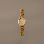 The Oval Link Timepiece Set features a gold-tone watch with a round face and beaded link bracelet, shown against a plain beige background.
