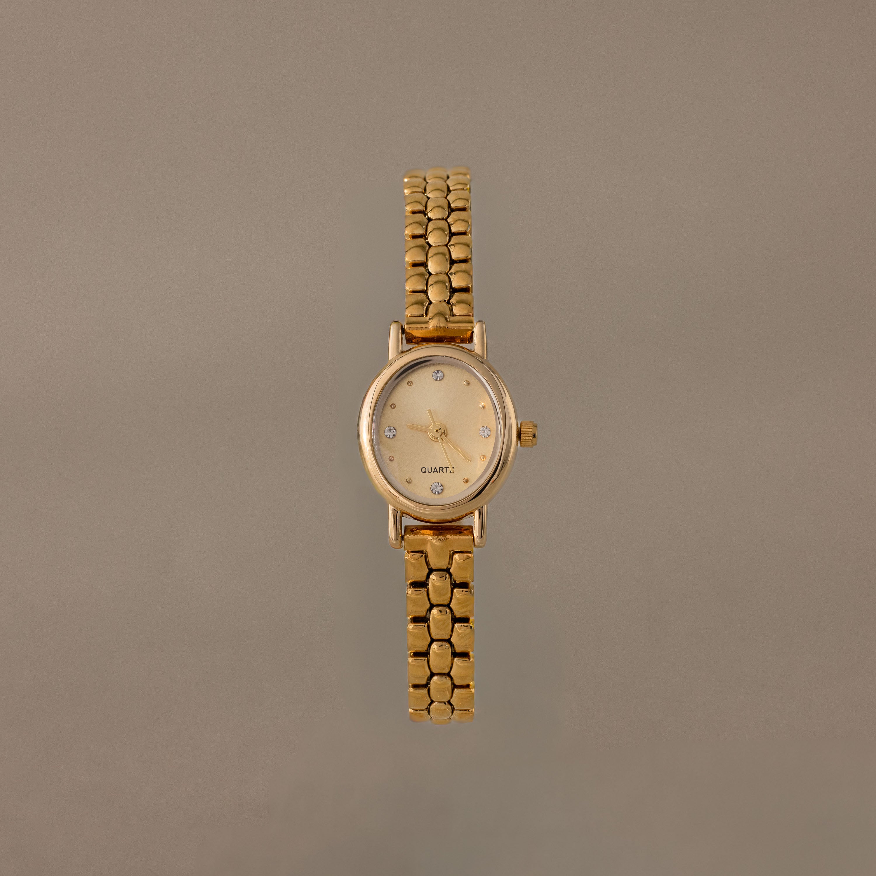 The Oval Link Timepiece Set features a gold-tone watch with a round face and beaded link bracelet, shown against a plain beige background.