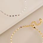 A dainty gold bracelet and the Josephine Chain Bracelet in Sterling Silver are elegantly displayed on a beige surface.
