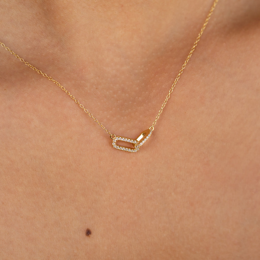 Close-up of a glamorous Pave Linked Pendant Necklace—a gold link chain with a rectangular, diamond-studded pendant—resting elegantly on the neck.
