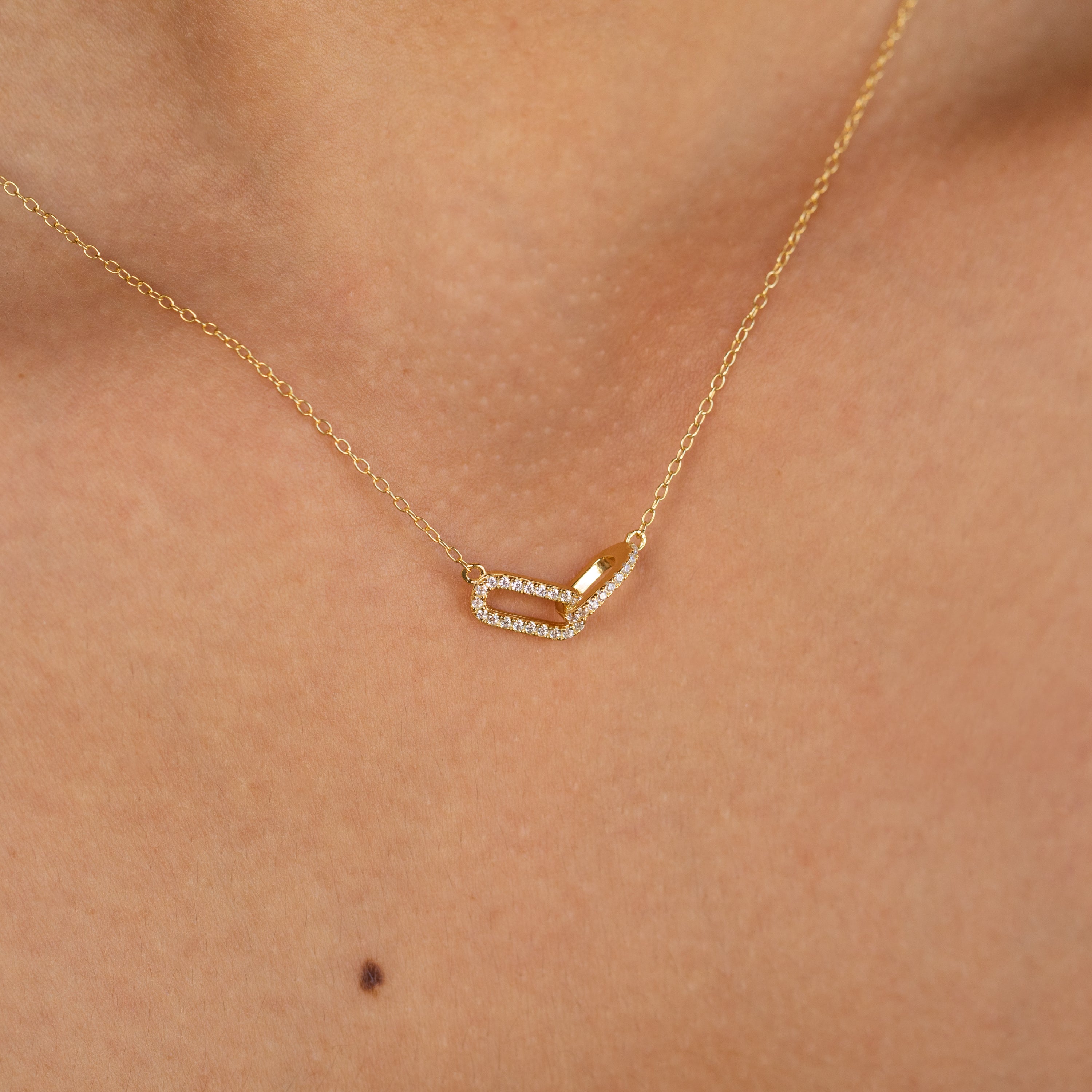 Close-up of a glamorous Pave Linked Pendant Necklace—a gold link chain with a rectangular, diamond-studded pendant—resting elegantly on the neck.
