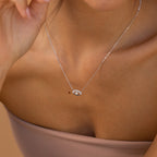 A close-up of a woman wearing the Amaryllis Pave Evil Eye Necklace in Sterling Silver, featuring an eye-shaped pendant with pave diamonds on her bare neckline.