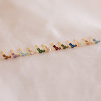 Bella Topaz Studs—gold earrings featuring vibrant stones in a neat row, displayed on soft light fabric. A timeless accessory and perfect gift for mothers and daughters.