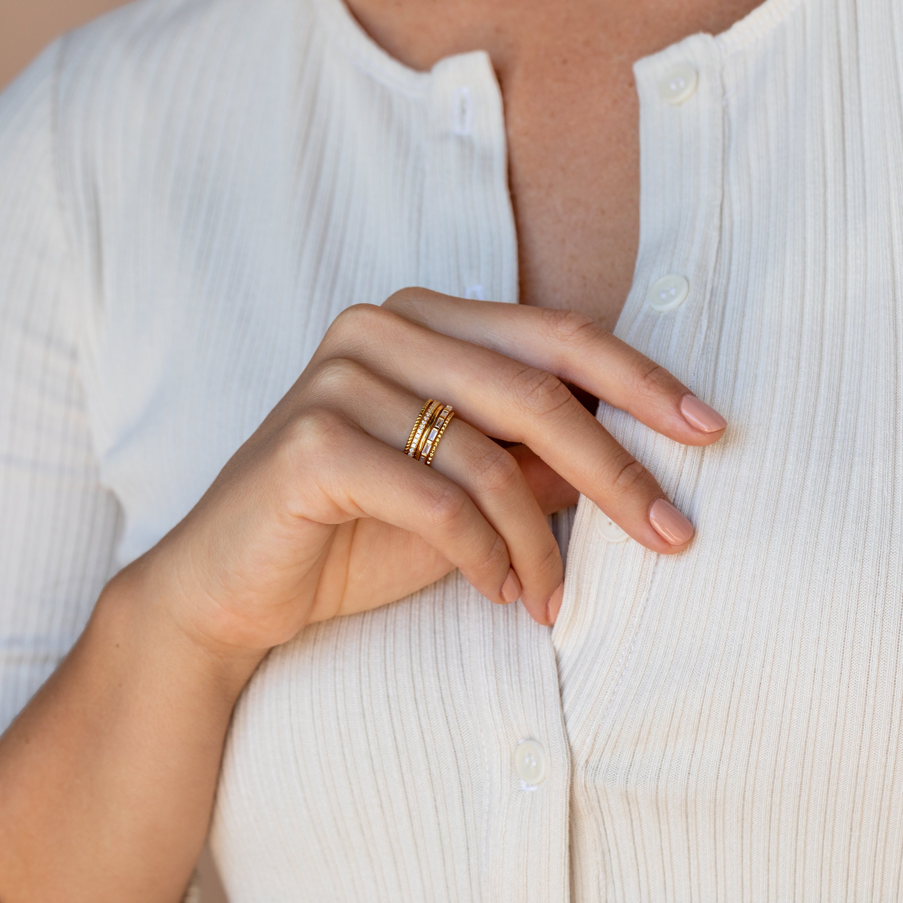 A close-up of a hand wearing the Thin Stacking Rings Set, showcasing a delicate and stylish ring stack on her finger.