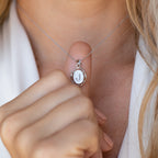 A person holding the Initial Pendant Necklace, a vintage-inspired accessory featuring a silver pendant with the letter J.