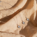 Three Initial Pendant Necklaces in Sterling Silver with oval charms displaying the letters K, M, and A rest on beige textured fabric—chic pieces for a vintage-inspired jewelry collection.