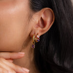 Close-up of a woman's ear adorned with Multiple Tapered Birthstone Huggies in Rose Gold—colorful statement hoops featuring vibrant birthstones and multicolored crystals.