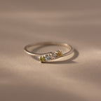 A delicate sterling silver stacking ring featuring three small gemstones in green, blue, and yellow—a beautiful Multiple Birthstone Curve Ring in Sterling Silver for personalized jewelry lovers.
