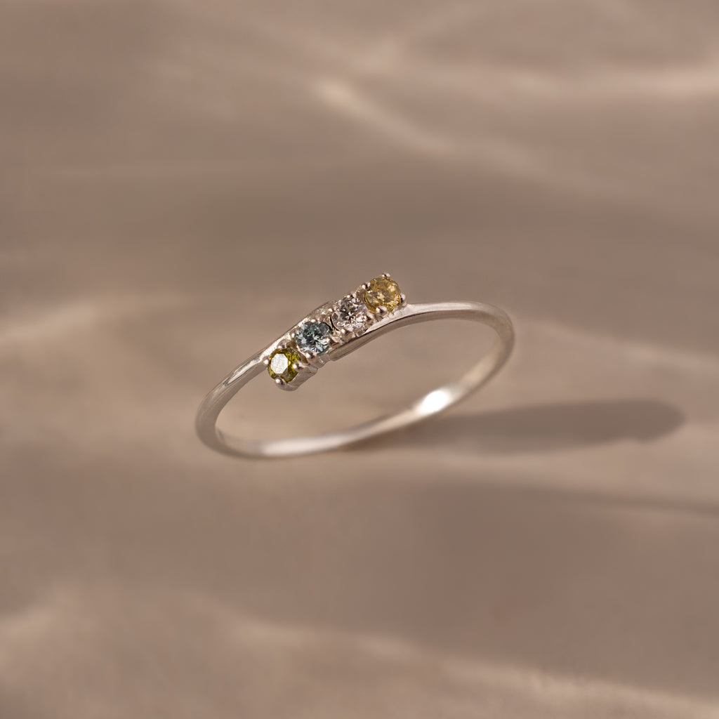 The Multiple Birthstone Curve Ring in Sterling Silver features small multicolored gemstones set in a row, making it ideal for stacking or as a personalized piece of jewelry.