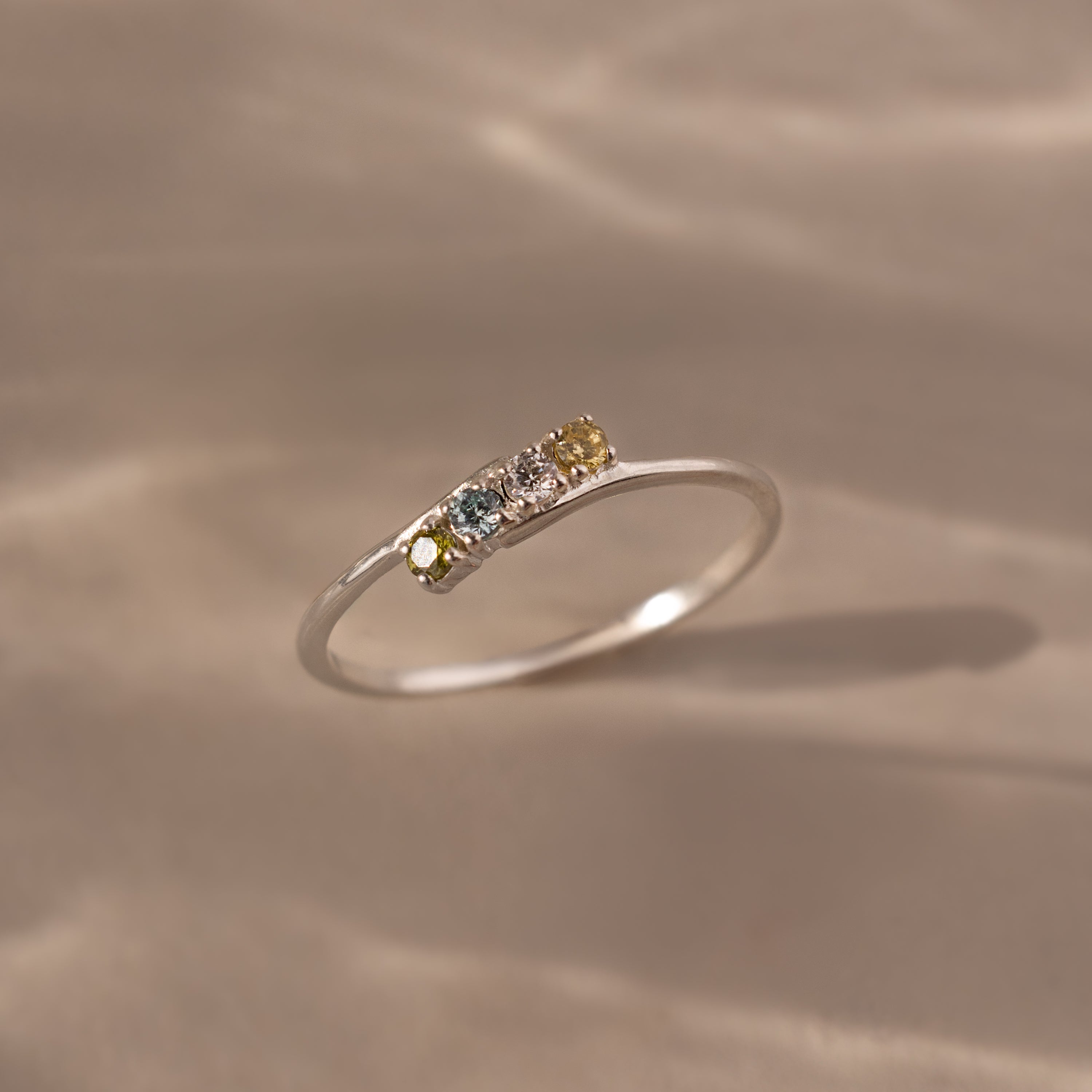 The Multiple Birthstone Curve Ring in Sterling Silver features small multicolored gemstones set in a row, making it ideal for stacking or as a personalized piece of jewelry.