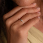 A close-up of a hand wearing the Multiple Birthstone Curve Ring in Sterling Silver, showcasing three small gemstones on the ring finger—a beautiful piece of personalized jewelry.