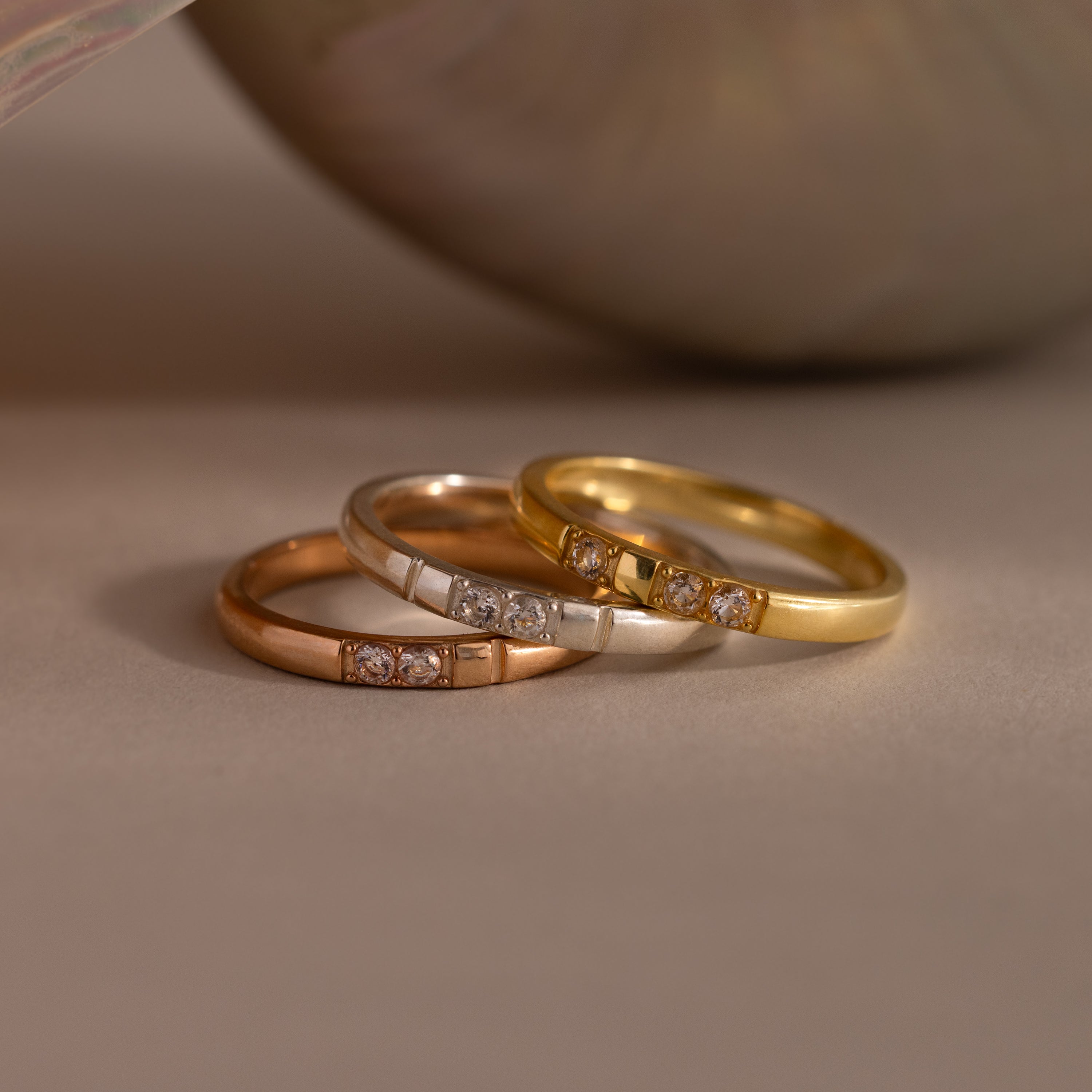 The Diamond Morse Code Ring in Sterling Silver, set with three small diamonds, rests on a beige surface—a meaningful symbol and a stylish accessory for any collection.
