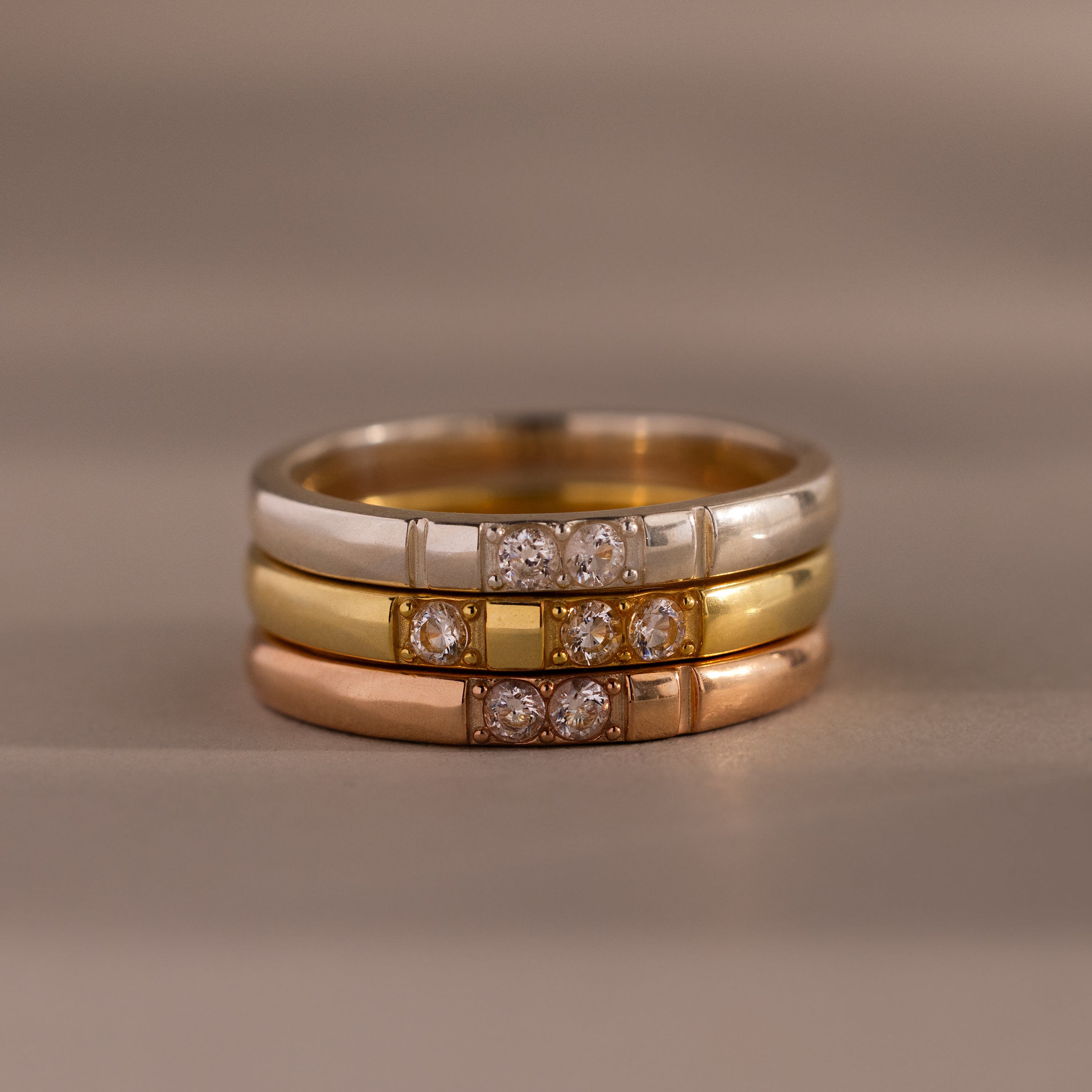 The Diamond Morse Code Ring features three stacked bands in silver, gold, and rose gold, each adorned with sparkling diamonds, displayed elegantly on a neutral background.
