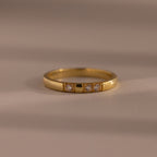 The Diamond Morse Code Ring in 18K Gold features three small diamonds set in the band, shown on a neutral surface—meaningful jewelry ideal for personal expression.