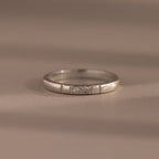 The Diamond Morse Code Ring in Sterling Silver features three small center diamonds, making it ideal as a symbolic or hidden message ring—shown here on a neutral surface.