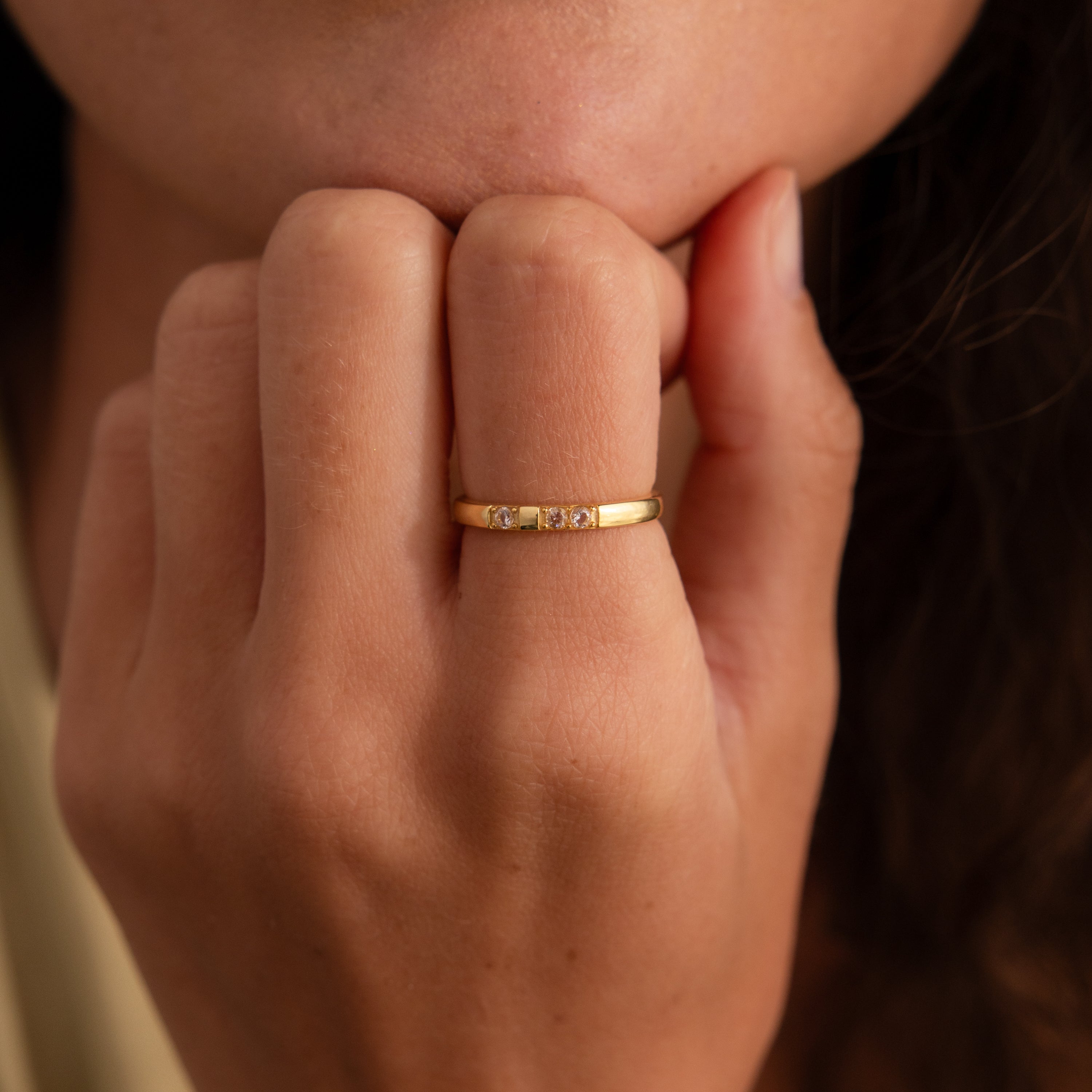 A hand near the face wears the Diamond Morse Code Ring, crafted in gold and accented with sparkling diamonds.